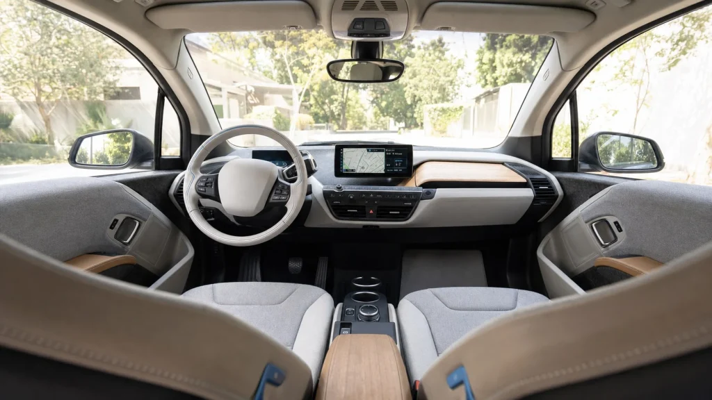 2020 BMW i3 Review: Used Price, Range, and Specs 6 The eco-friendly interior dashboard of a 2020 BMW i3 featuring open-pore eucalyptus wood trim and gray sustainable fabric seats.