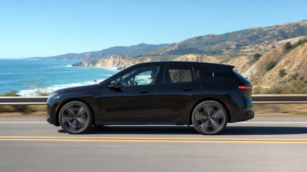 A black 2023 BMW iX M60 driving along a scenic California highway